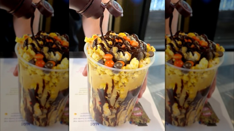 Cup of dirty popcorn from Urick Concessions with Reeses Pieces and chocolate sauce drizzled on top