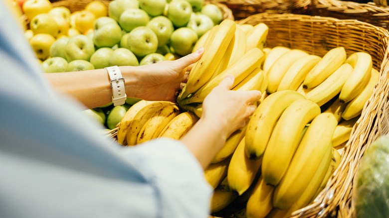 person grabbing supermarket bananas