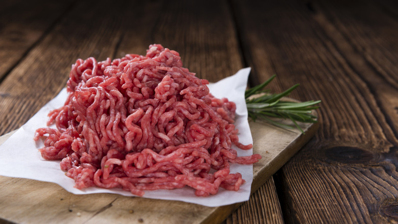 A portion of raw ground beef on a piece of wax paper on a chopping board