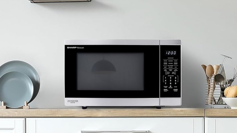 Sharp microwave on counter with plates and utensils