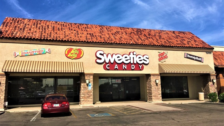 The outside of a candy store with various sweet brands on the wall