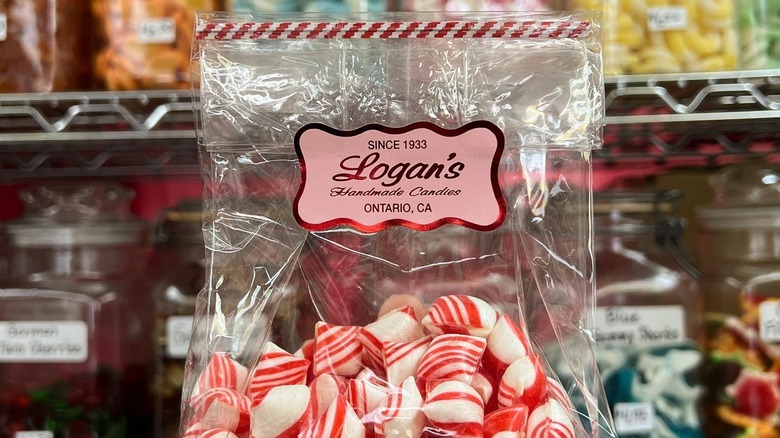 A bag of Logan's candy with candy on shelves behind