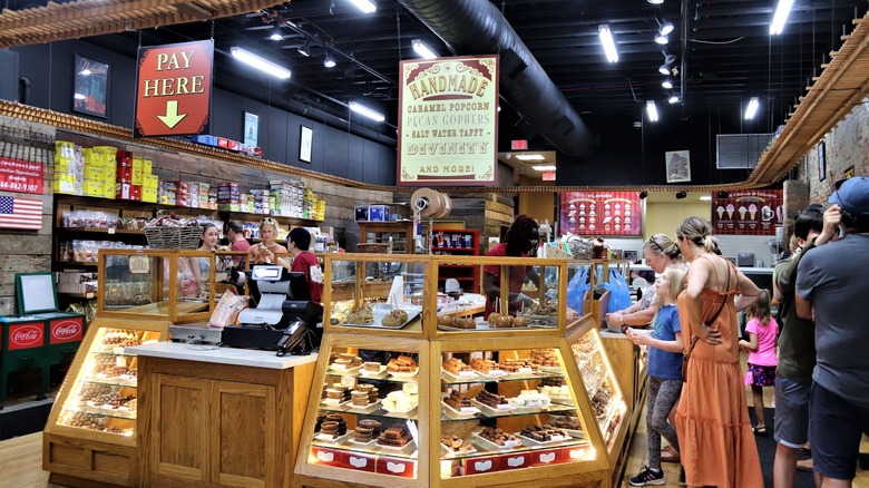 People shopping in a candy store with a pay here sign