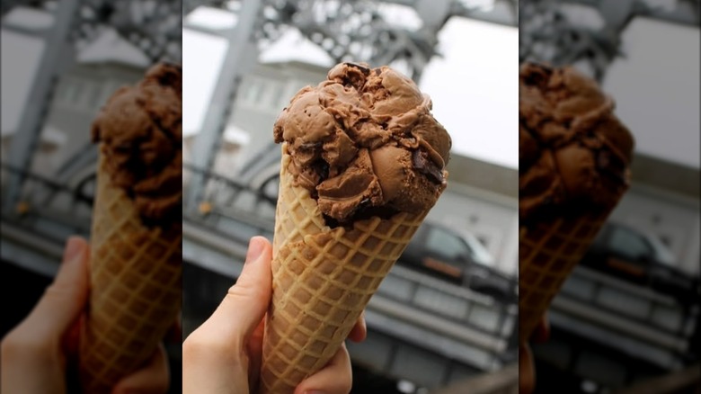 Hand holding cone of chocolate ice cream