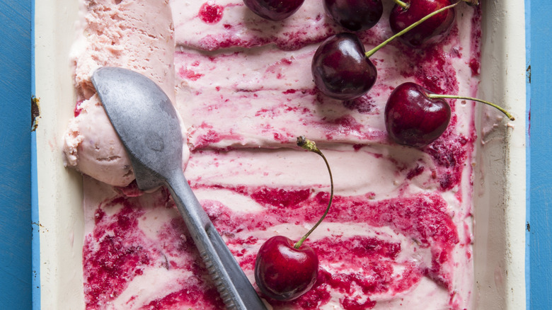 Cherry ice cream being scooped out of dish
