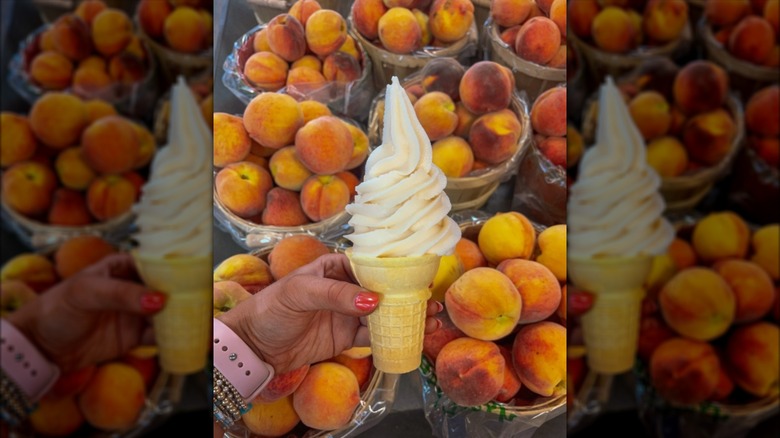 Hand holding cone of peach ice cream with fresh peaches in background