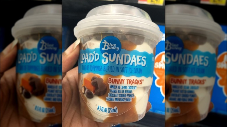 Hand holding tub of Blue Bunny Bunny Tracks ice cream