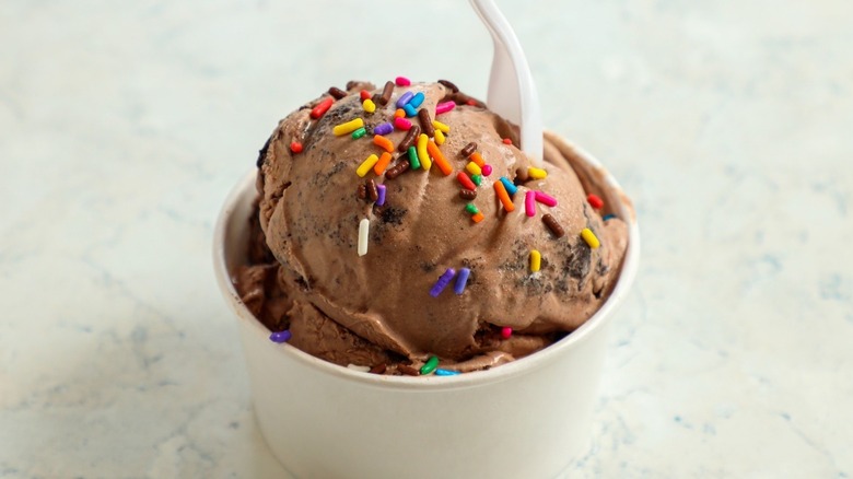 Close up of tub of chocolate ice cream with rainbow sprinkles