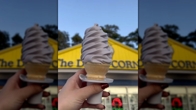 Hand holding blueberry ice cream cone outside ice cream store