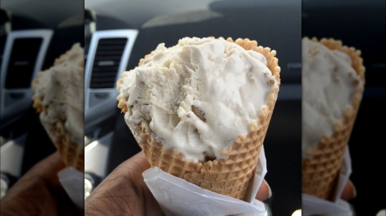 Hand holding cone filled with walnut ice cream