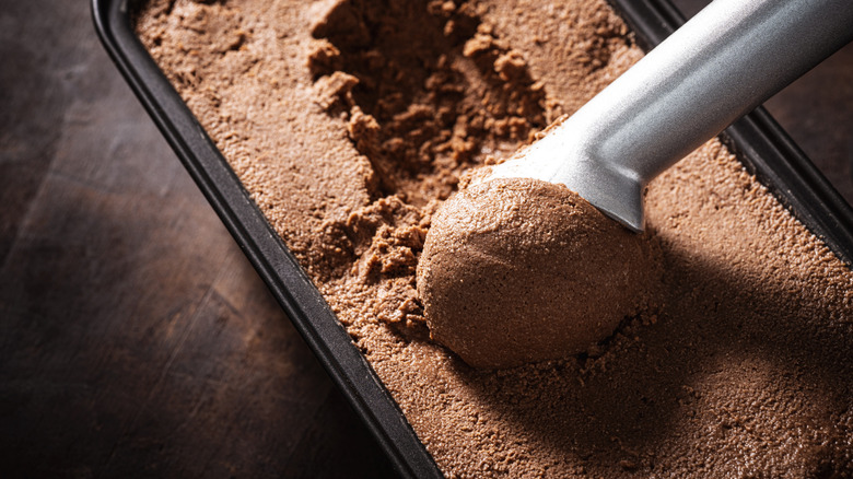 Scooping chocolate ice cream from pan