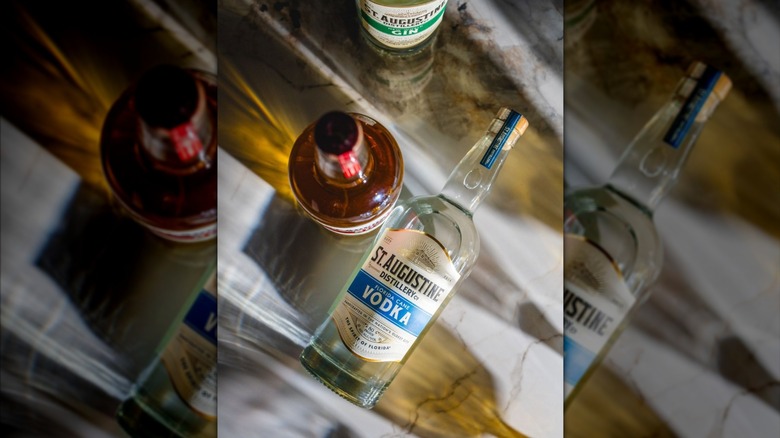 St. Augustine vodka laid flat on a table with other spirits gathered around.