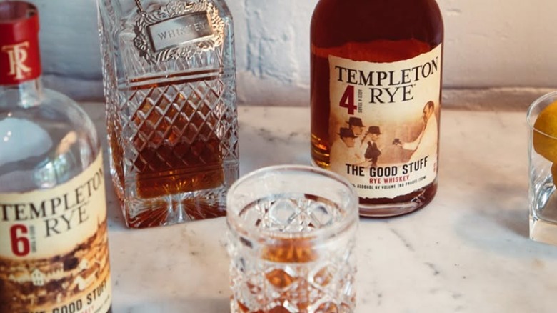 Bottles of Templeton Rye spread out with crystal decanter and whiskey glass.