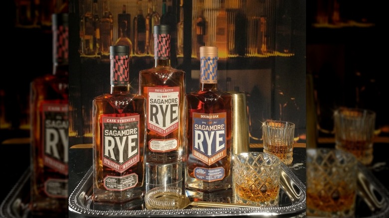 A silver tray full of bottles of Sagamore Rye with crystal glasses and bar tools.