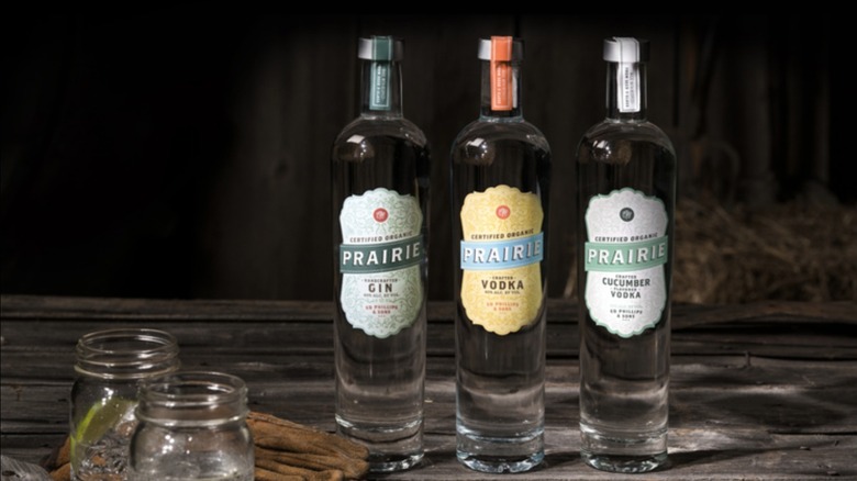 A suite of Prairie Organic Spirits bottles starting with Gin, Vodka, and Cucumber Vodka in a dark bar.