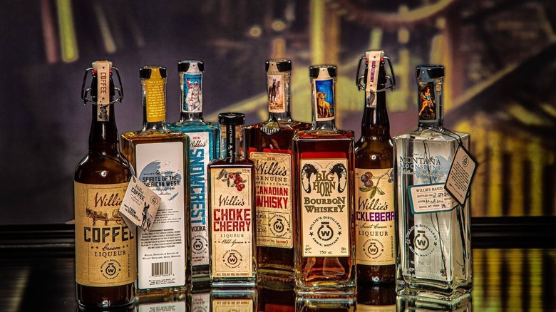 A collection of Willie's spirits in different bottles with Western inspired labels sitting on a reflective bartop.