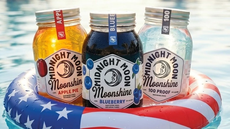 Three expressions of Midnight Moon Moonshine in mason jars and American flag pool floatie.