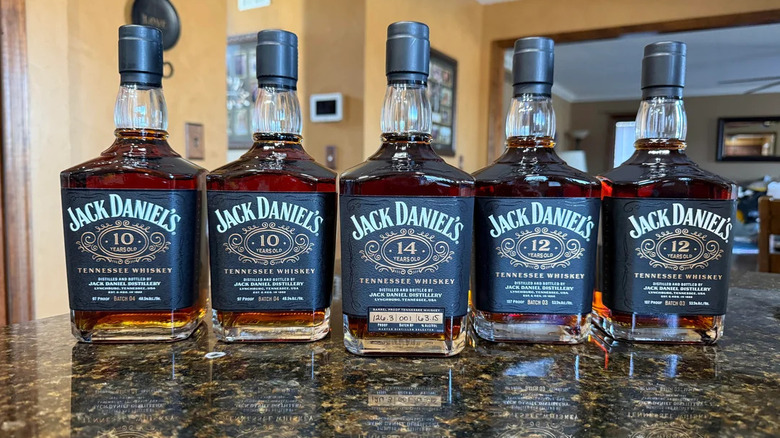 Five bottles of Jack Daniel's whiskey on a marble countertop in a home kitchen.