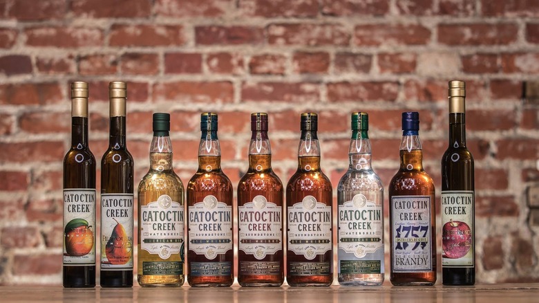 A lineup of various Catoctin Creek bottles against a brick wall.