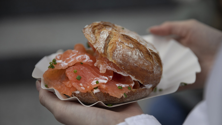 Person holding a smoked salmon sandwich