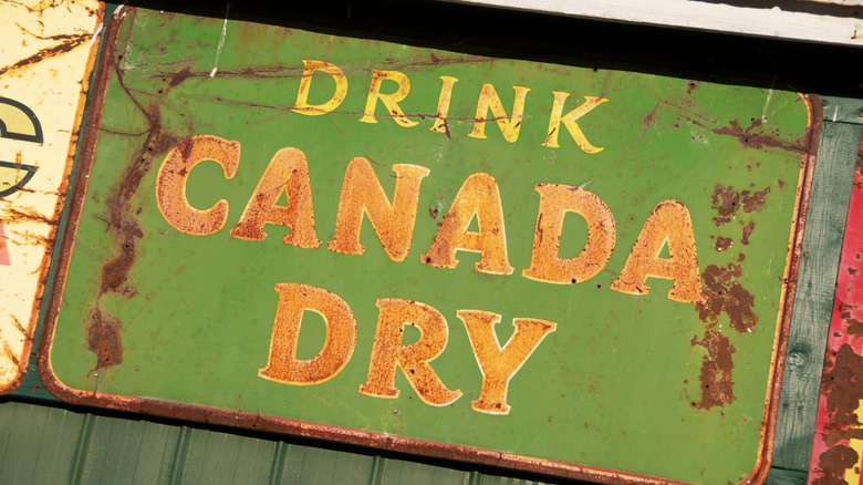 A rusty vintage sign advertising Canada Dry ginger ale.