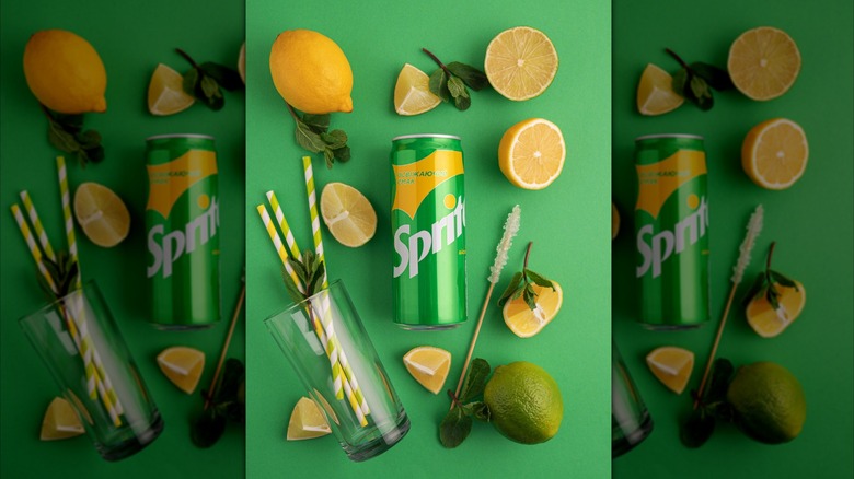 A can of Sprite surrounded by fresh soda ingredients and a tipped over cup with three straws.