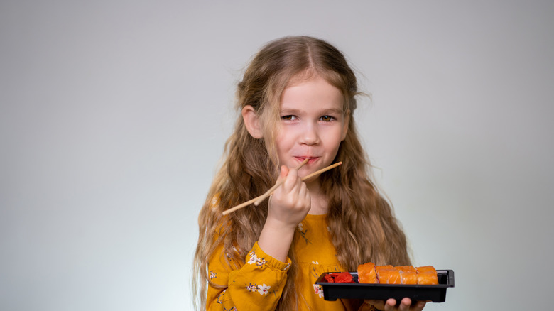 A child sucking the end of a chopstick