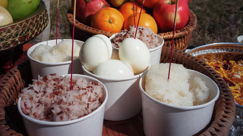 A funeral offering including bowls of rice with incense sticks stuck in them