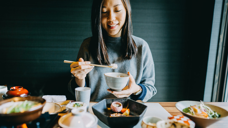 A woman eating rice from a bowl with chopsticks