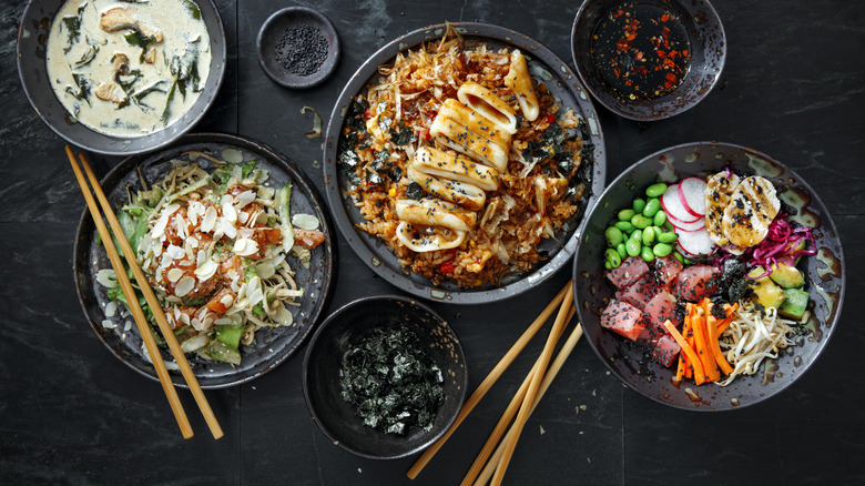 A variety of Japanese dishes and sets of chopsticks on a table