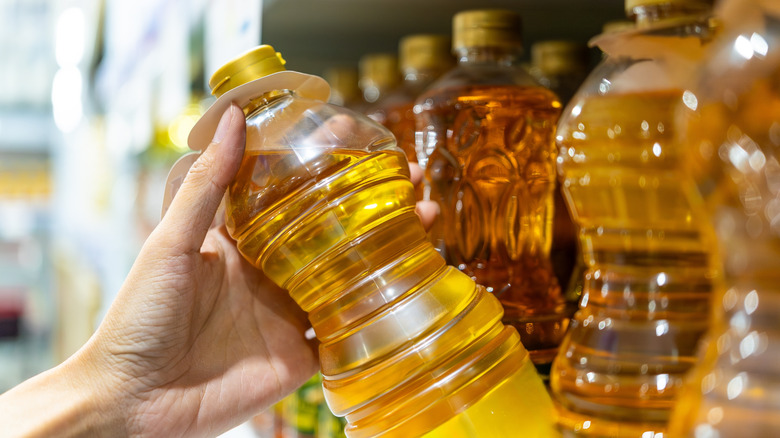 Hand taking a plastic bottle of cooking oil from the store shelf