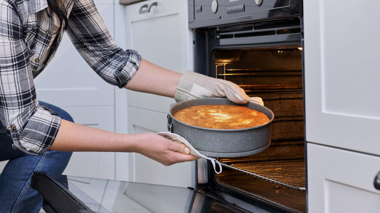 Person removing cake from oven