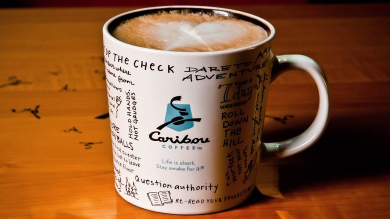 Coffee inside of a Caribou Coffee mug on a wooden table