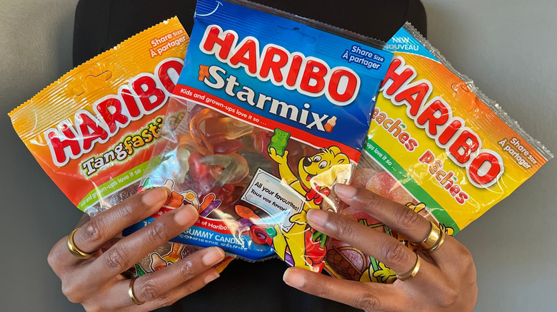 person holding bags of different Haribo gummy candies
