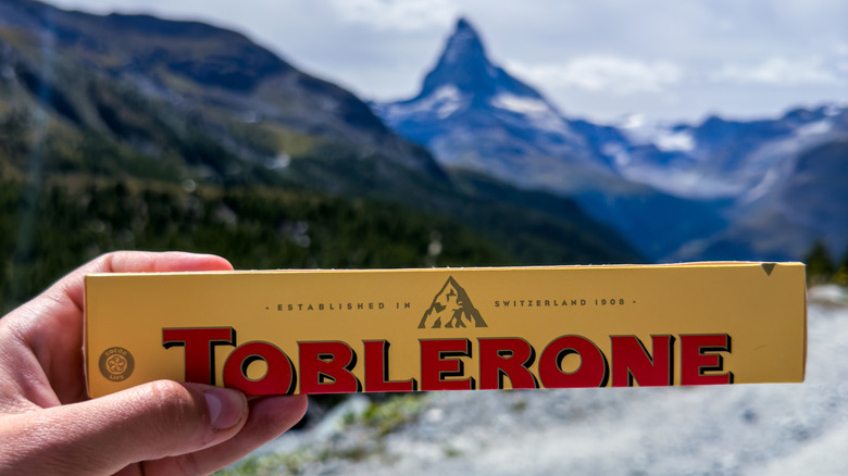 hand holds Toblerone chocolate bar with the Matterhorn mountain in the background