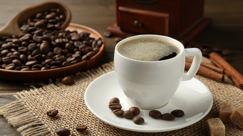 cup of black coffee with coffee beans around