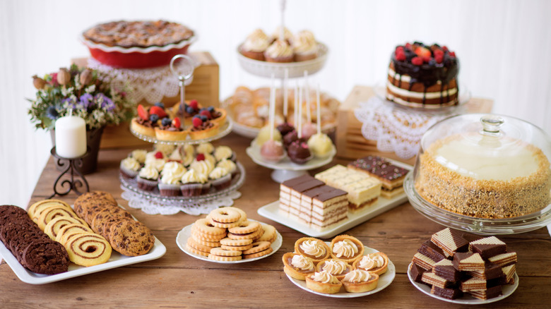 A table full of different desserts, such as cookies, cupcakes, cake pops, large cakes, and more.