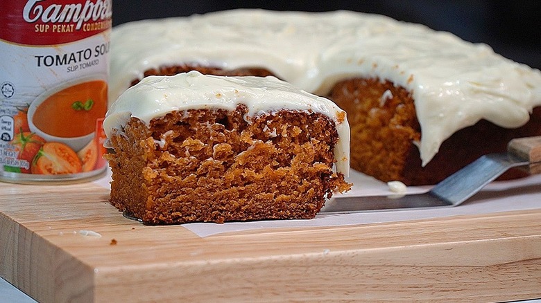 A slice of tomato soup cake on wooden board in front of soup can