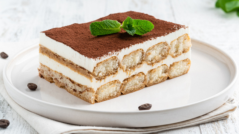 tiramisu on a white place with coffee beans on white table