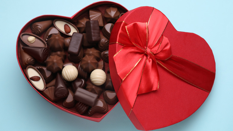 Open, heart-shaped box of chocolates on blue background