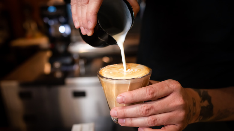 A barista pouring a flat white
