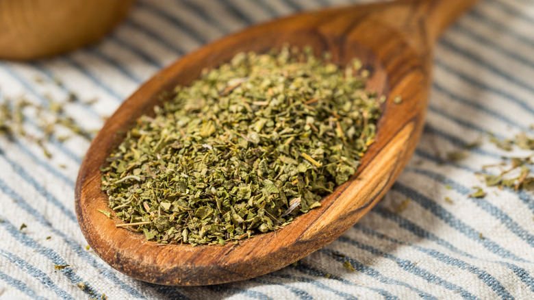 A small pile of dried oregano on a wooden spoon
