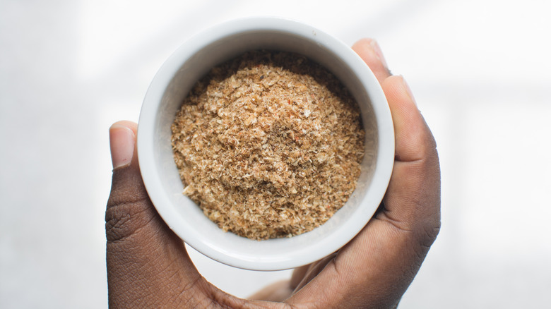hand holding a container of Nigerian fish powder