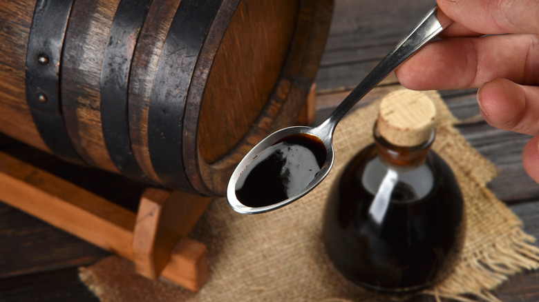 Spoonful of balsamic vinegar next to a cask