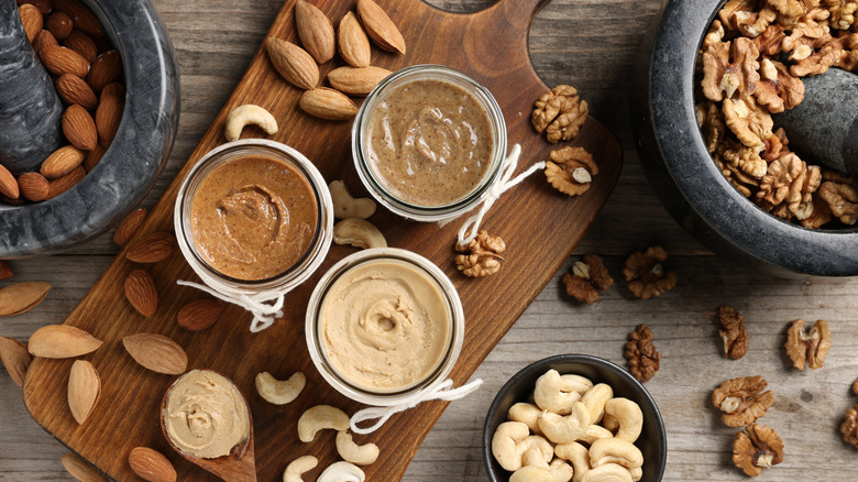 Almond, walnut, and cashew butter on board with nuts