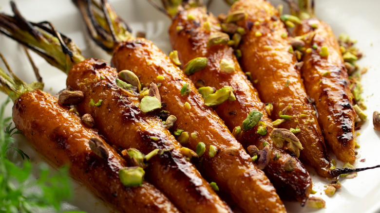 Closeup view of roasted carrots on a plate topped with pistachios