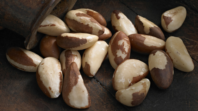 Brazil nuts on a table tumbling out of a ceramic container