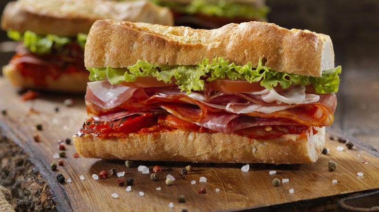 Italian deli sub sandwich on board next to salt and pepper granules