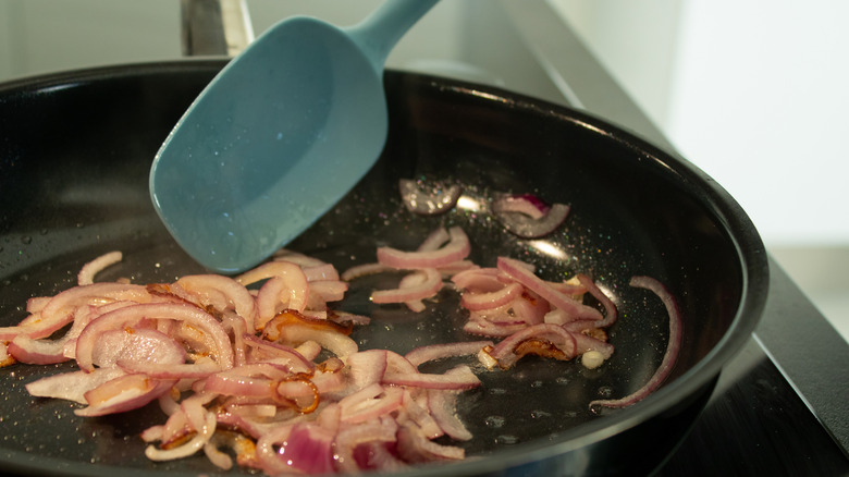 Spatula in a pot with cooking onions