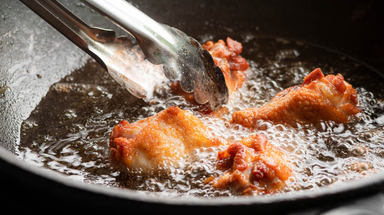 Chicken wings frying in pan